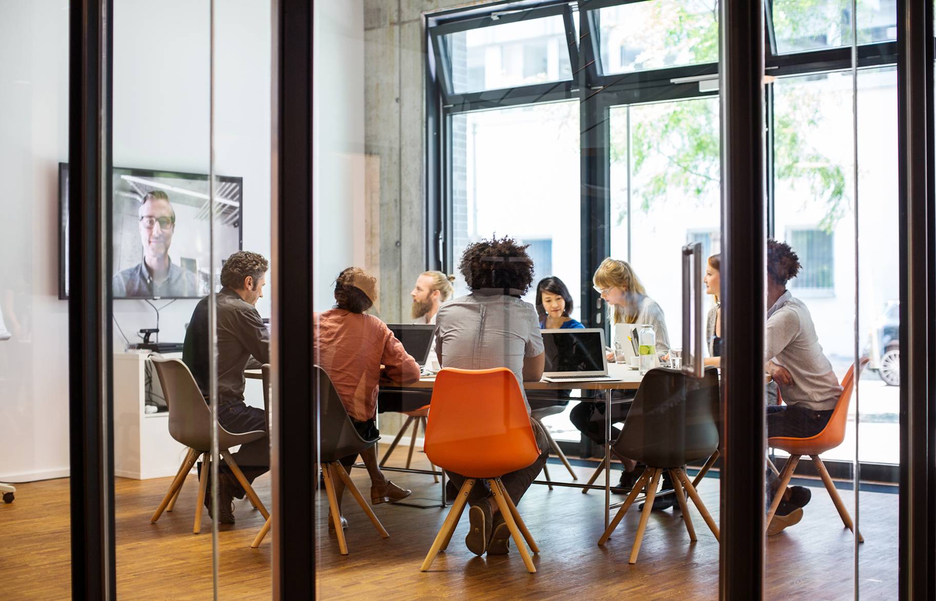 Group of business people meeting in modern conference room with a leader on the big screen