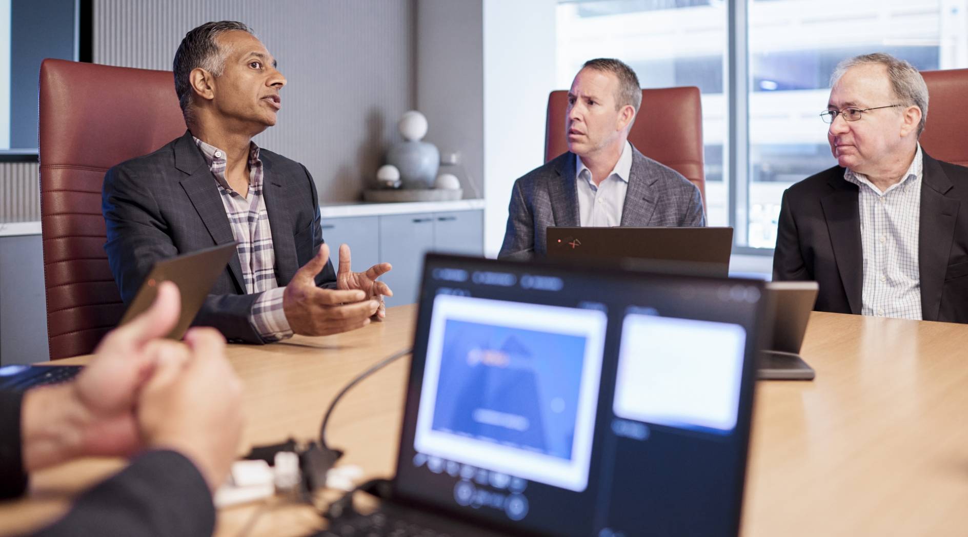 Four Novo Advisors team members having a discussion in a conference room.