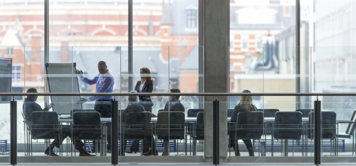 Group of people behind large glass windows having a meeting