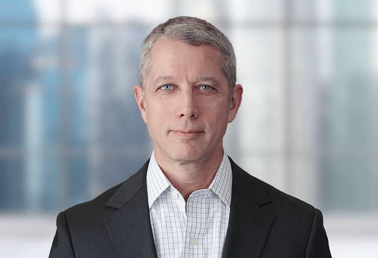 Picture of Paul Kostolansky in front of a blurred office image