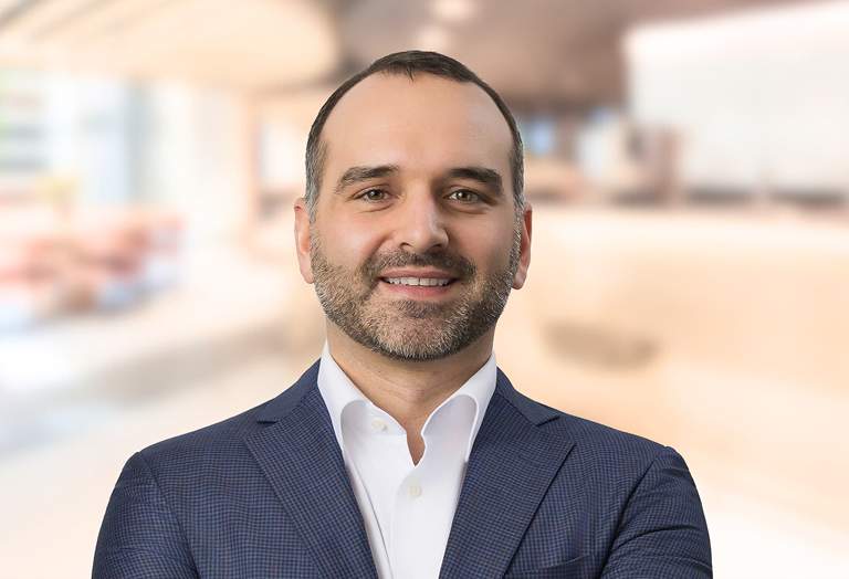 Connor Dougan, Director in front of a soft focus architectural background